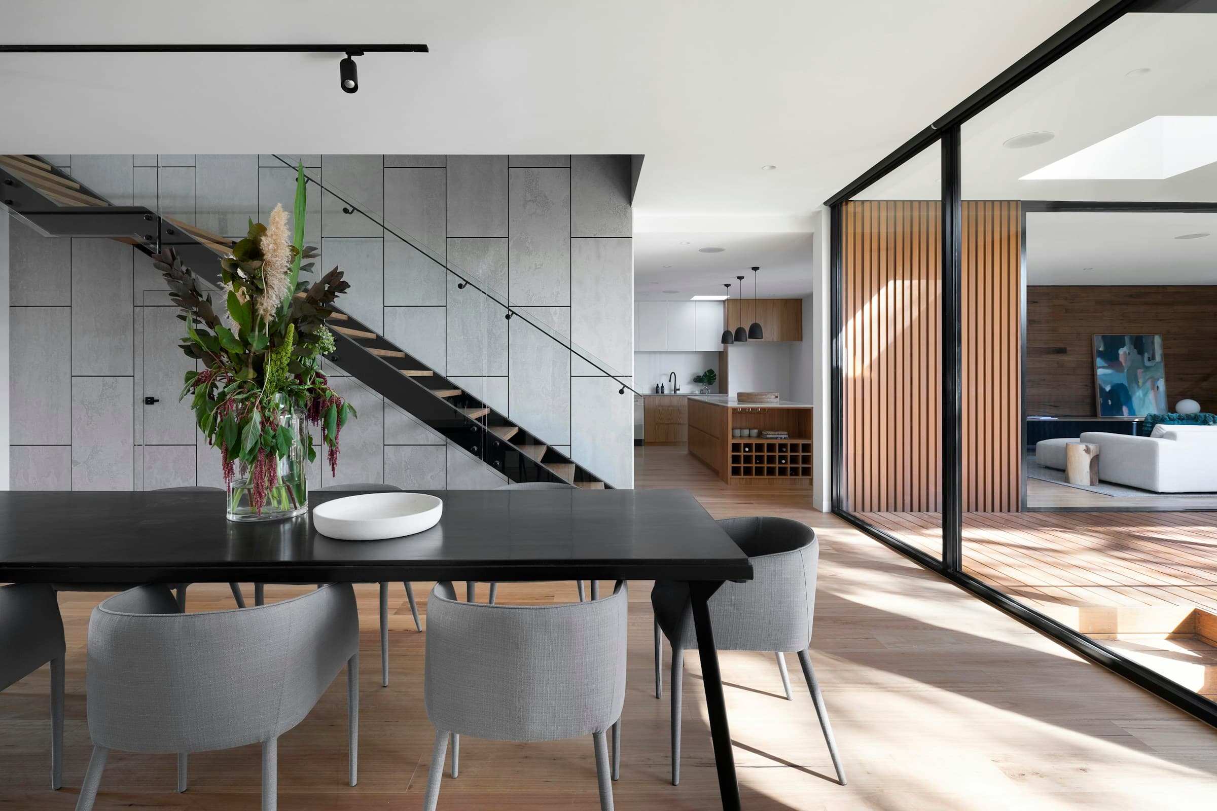 Modern villa med stora glaspartier och grönskande uteplats
